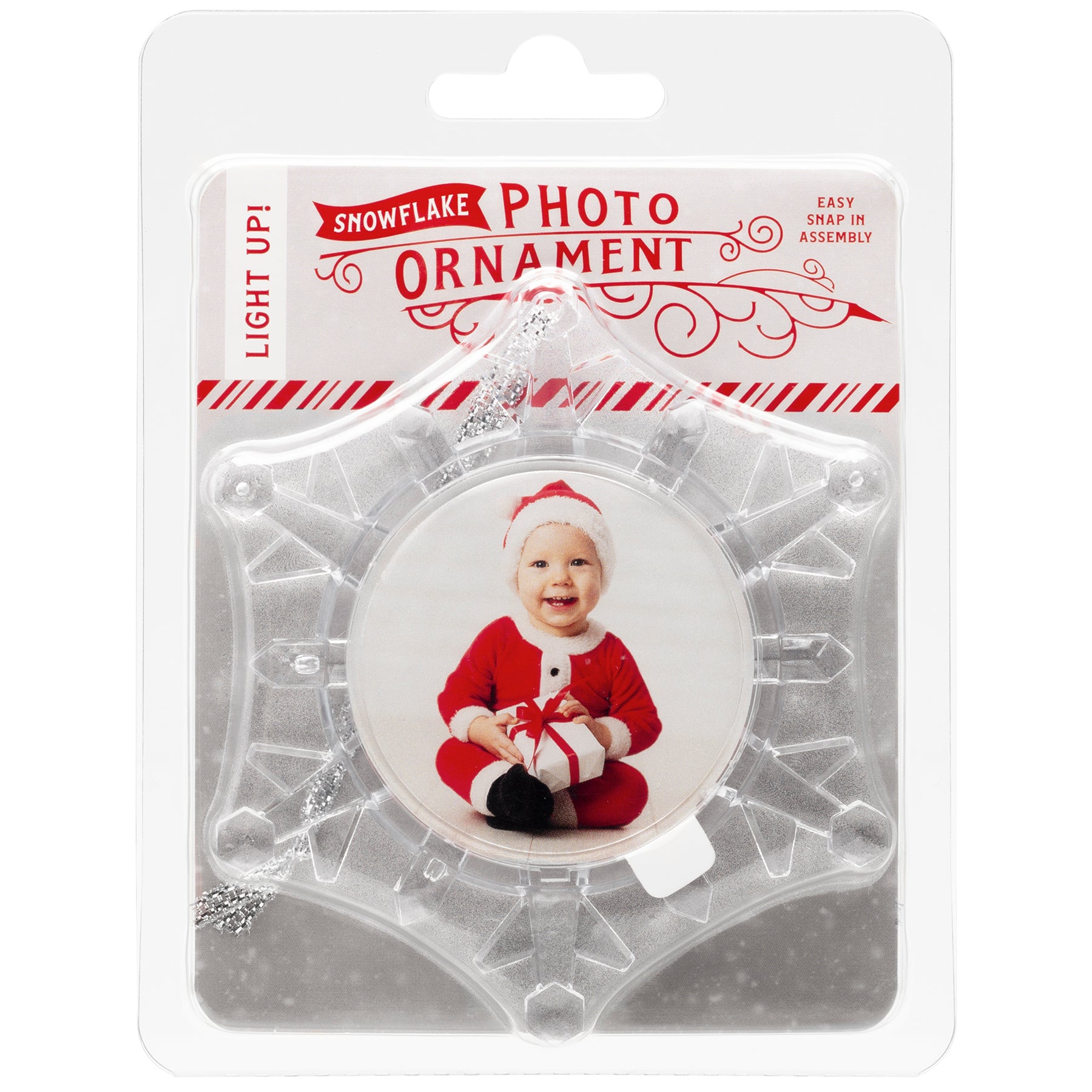 A clear plastic snowflake-shaped photo ornament with a beveled edge, displaying a photo of a smiling child in Santa attire in the center displayed in full-color retail packaging.