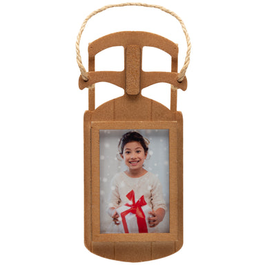A wooden sled-shaped photo ornament with a loop of twine used to hang the ornament on a Christmas tree.