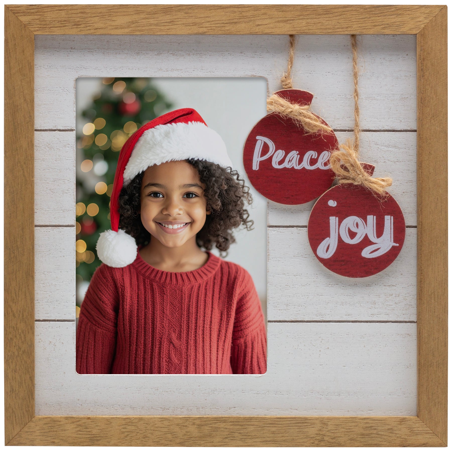 Child wearing a Santa hat with Christmas decorations and ornaments in a wooden frame.