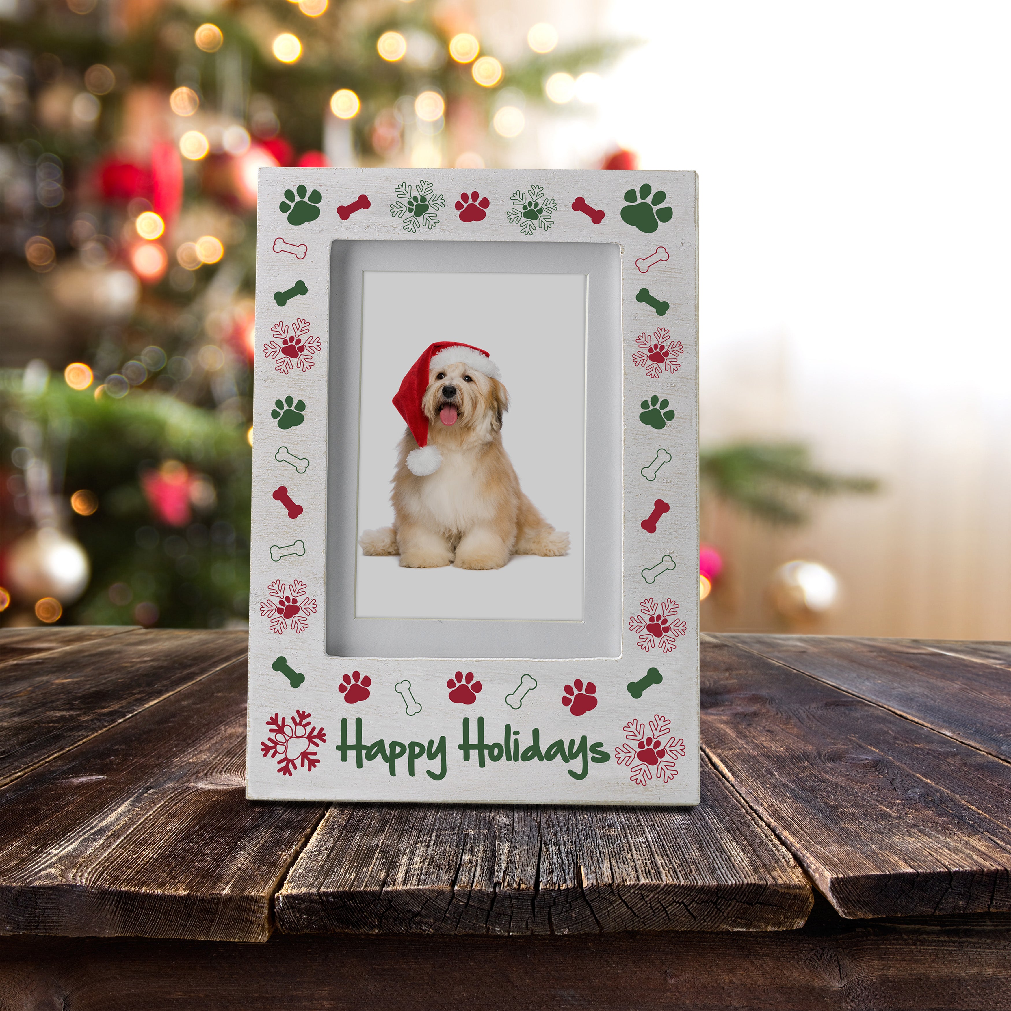 A white wooden picture frame with the phrase "Happy Holidays" at the bottom with a border of paw prints, bones, and snowflakes displayed on a festive lifestyle background.