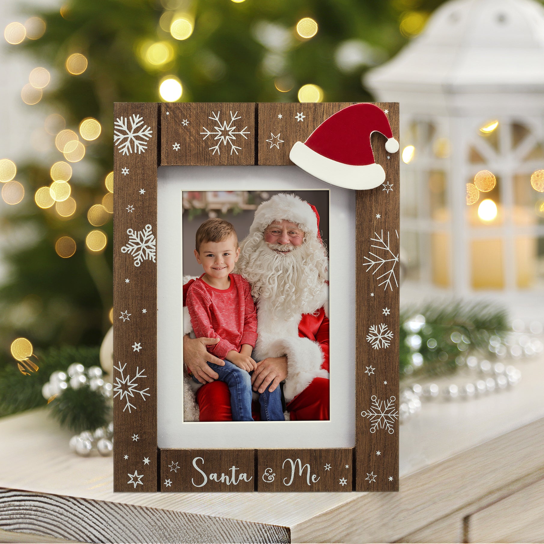 A wooden picture frame with a shiplap design and white snowflakes, the phrase "Santa & Me" at the bottom, and a red Santa hat in the top corner displayed on a table with a festive background.