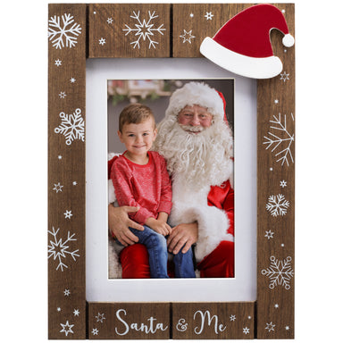 A wooden picture frame with a shiplap design and white snowflakes, the phrase "Santa & Me" at the bottom, and a red Santa hat in the top corner.