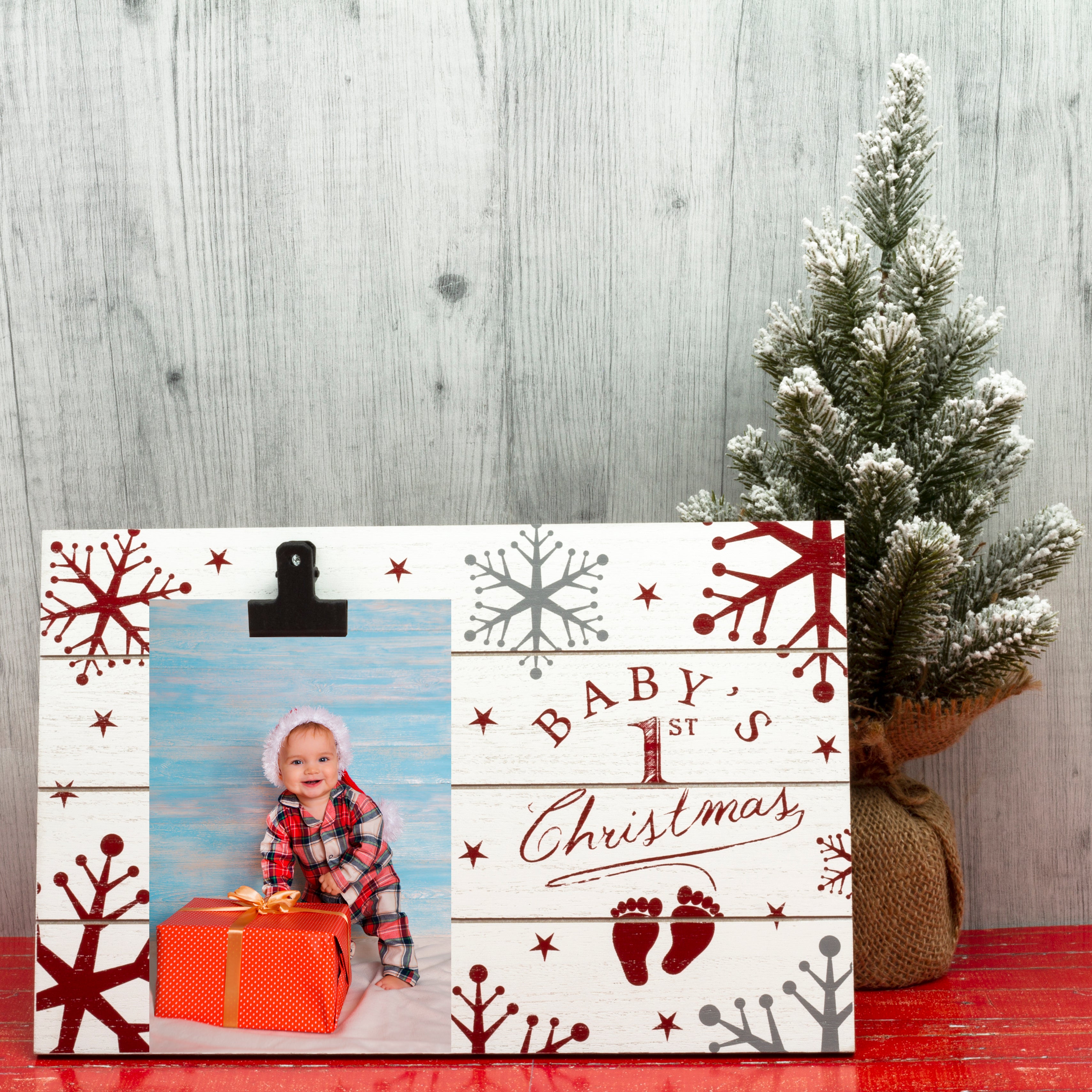 A wooden clipboard picture frame with a Christmas theme, featuring the text 'Baby's 1st Christmas' decorated with snowflakes and stars on a festive lifestyle background.