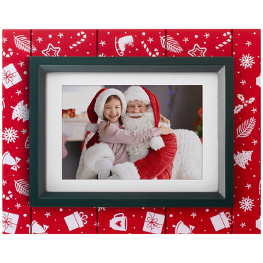 A red wood picture frame with black trim, with white stenciled decorations such as ice skates, presents, candy canes, and more.