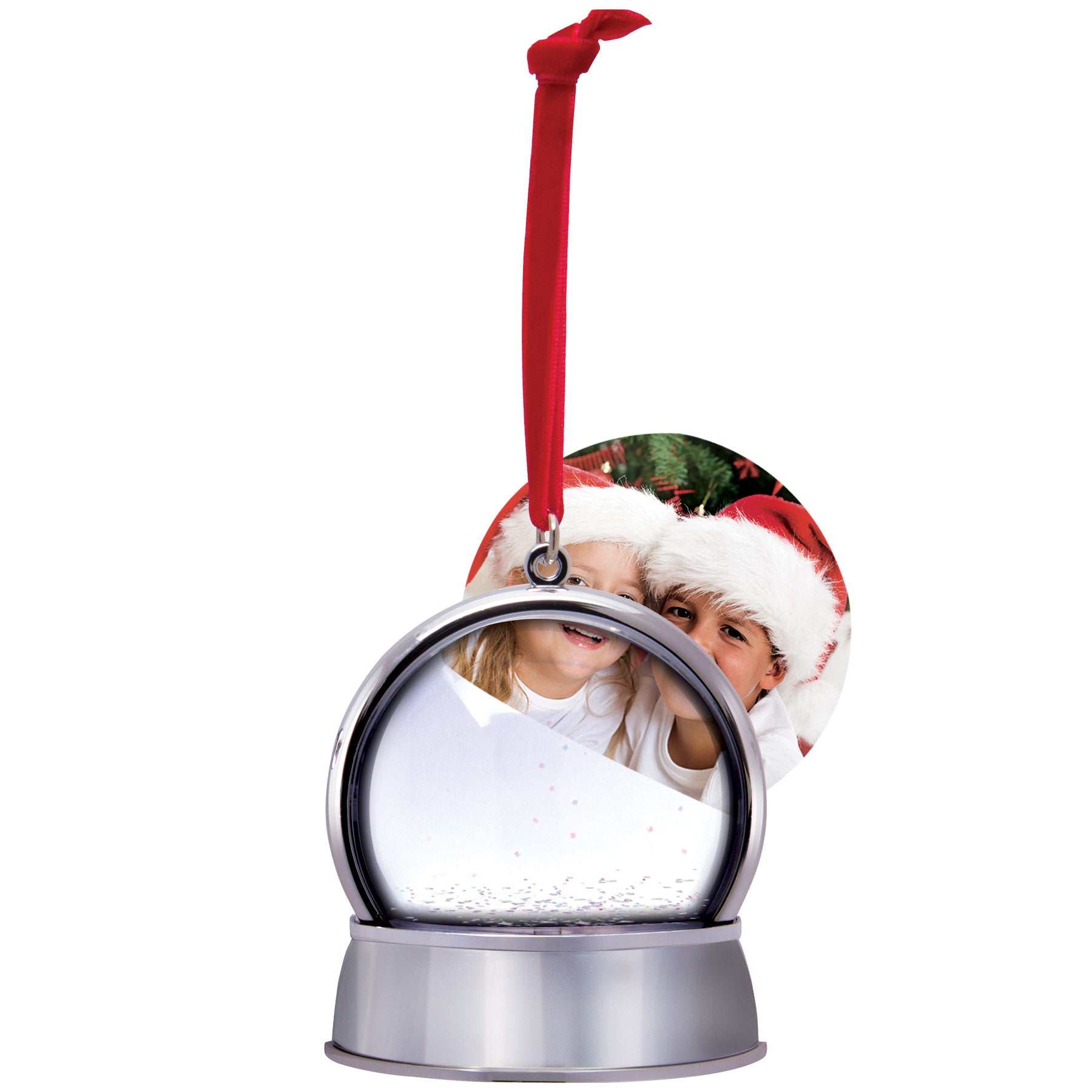 A magnetic snow globe ornament with a silver base and a curved photo being inserted into the globe. The ornament has a red velvet string for hanging and features white snow and iridescent glitter.