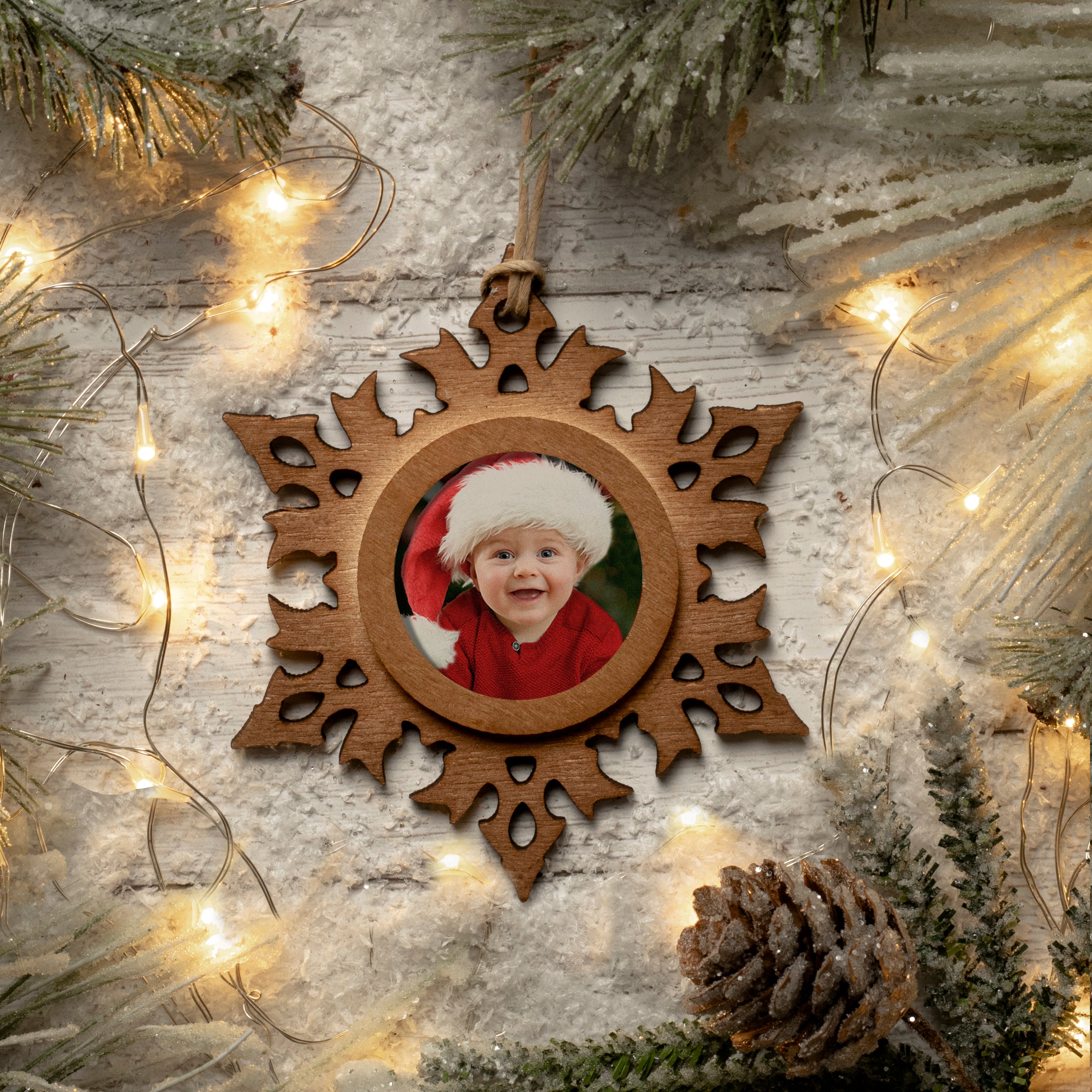 A wooden snowflake-shaped photo ornament with a photo of a smiling child in the center, displayed against a festive lifestyle background.