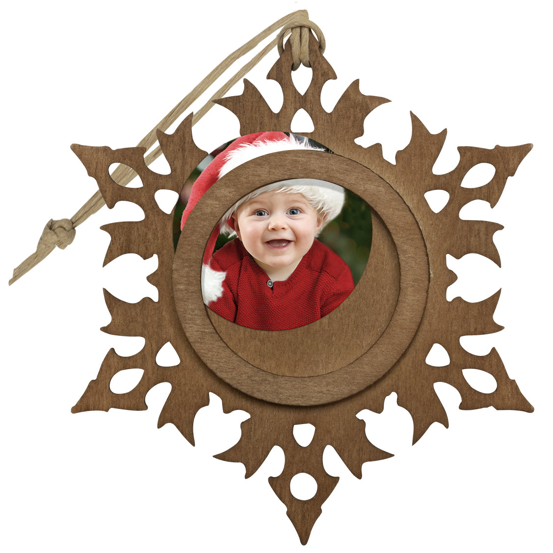 A wooden snowflake-shaped photo ornament with a photo of a smiling child about to be inserted into the center of the ornament.