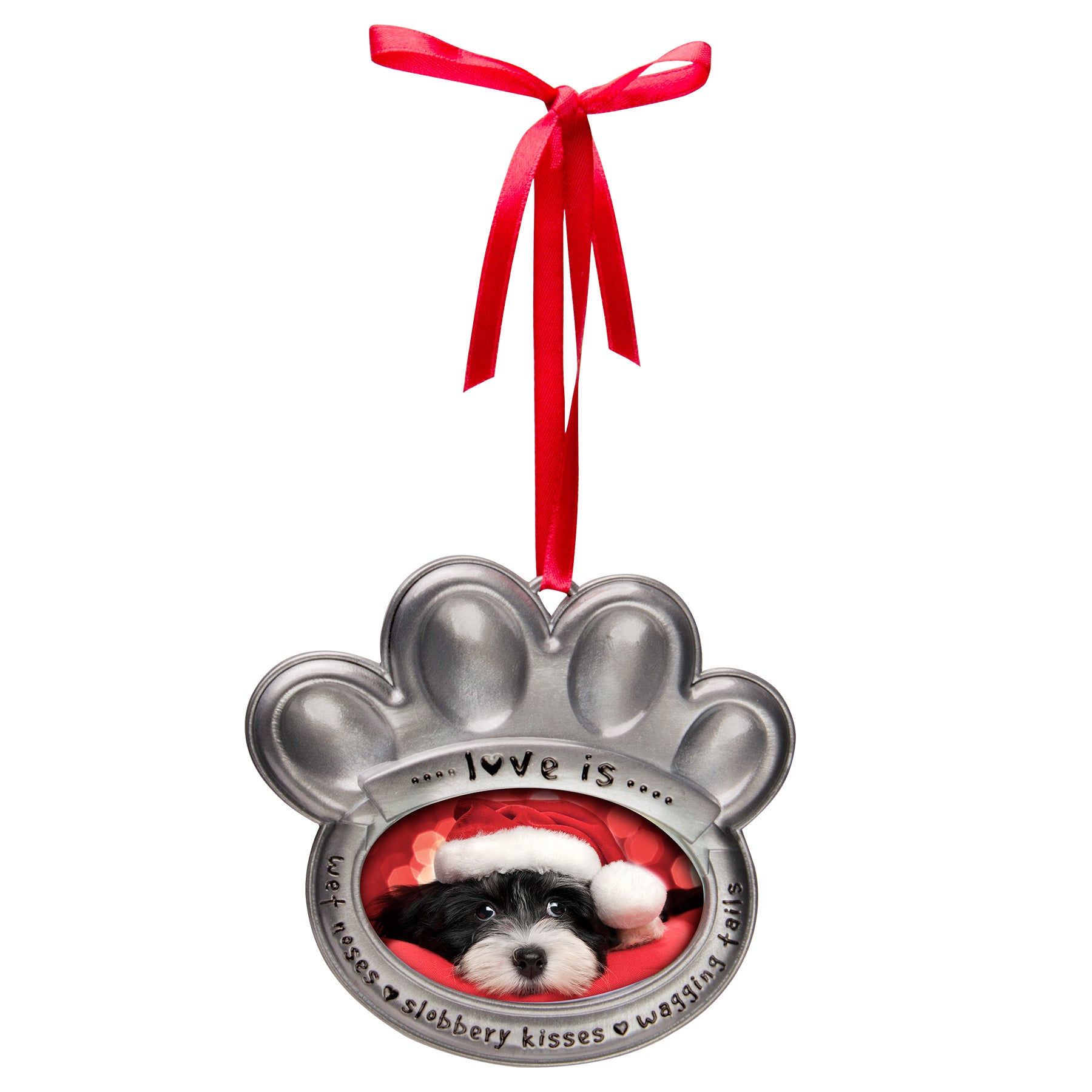 A pewter photo ornament in the shape of a paw print with the text 'love is wet noses, slobbery kisses, wagging tails" hanging from the red velvet ribbon displayed on a white background.