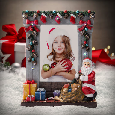 A gray colored light-up resin picture frame with hand painted details featuring garland, stockings, presents, Santa, and more on a festive lifestyle background.