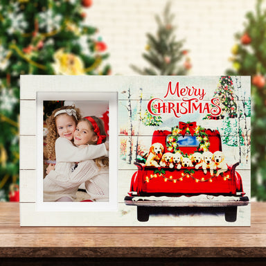 A wooden picture frame with a rustic design, featuring the back of a red truck filled with golden retriever puppies, surrounded by a Christmas-themed scene with trees and decorations on a festive lifestyle background.
