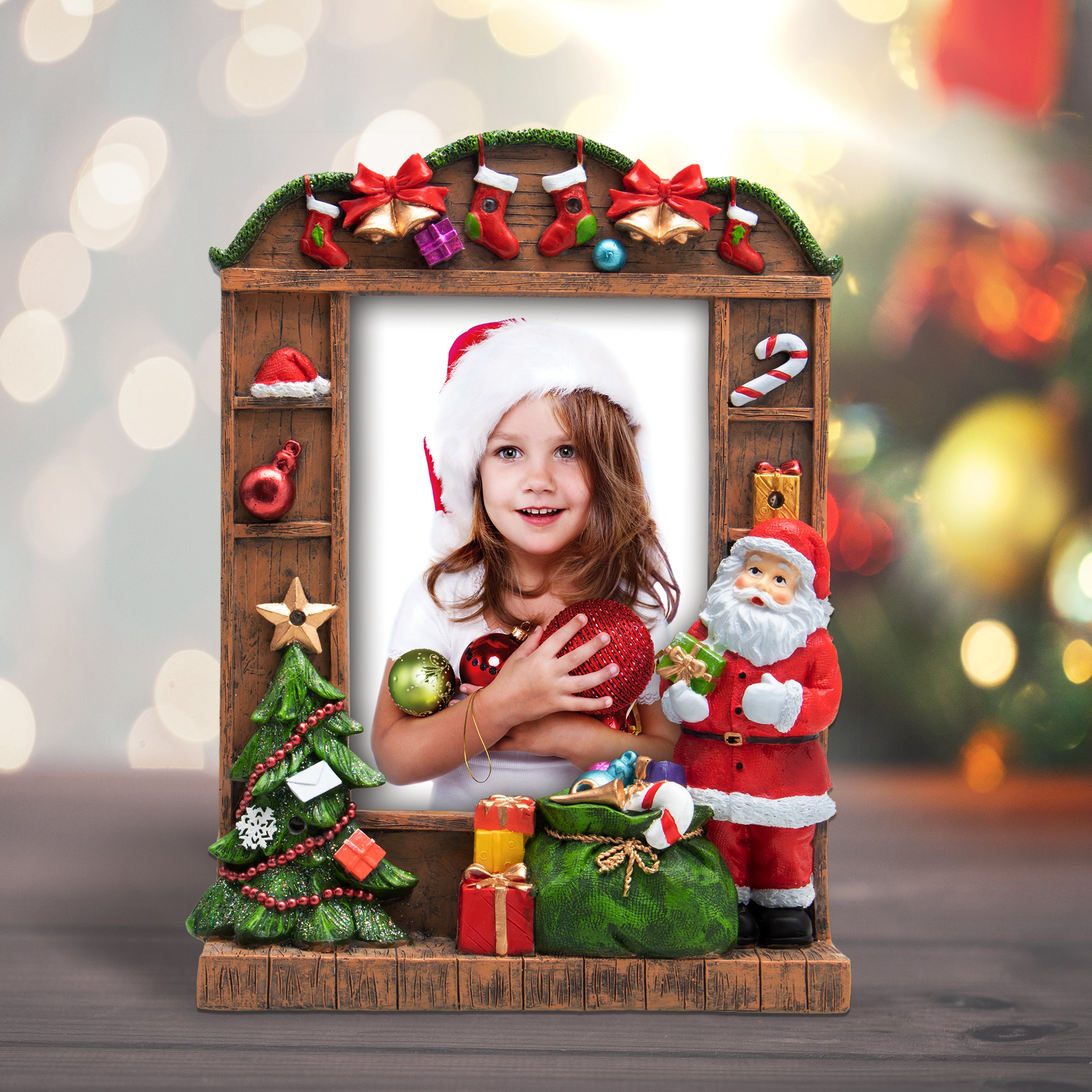 A resin picture frame with a Christmas theme, featuring Santa Claus, a Christmas tree, and wrapped presents. The frame is designed to hold a 5" x 7" photo and has multicolored lights along its border on a festive lifestyle background.