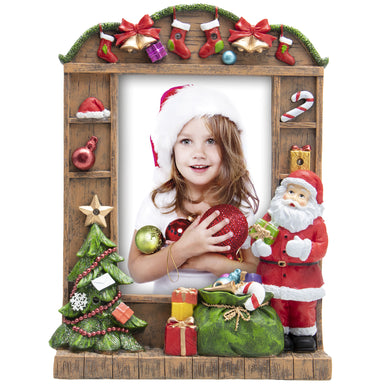 A resin picture frame with a Christmas theme, featuring Santa Claus, a Christmas tree, and wrapped presents. The frame is designed to hold a 5" x 7" photo and has multicolored lights along its border.