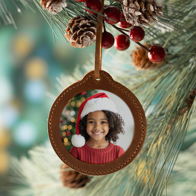 A B2B round custom browen leather photo Christmas ornament for holding festive photos. Used as a special event giveaway.