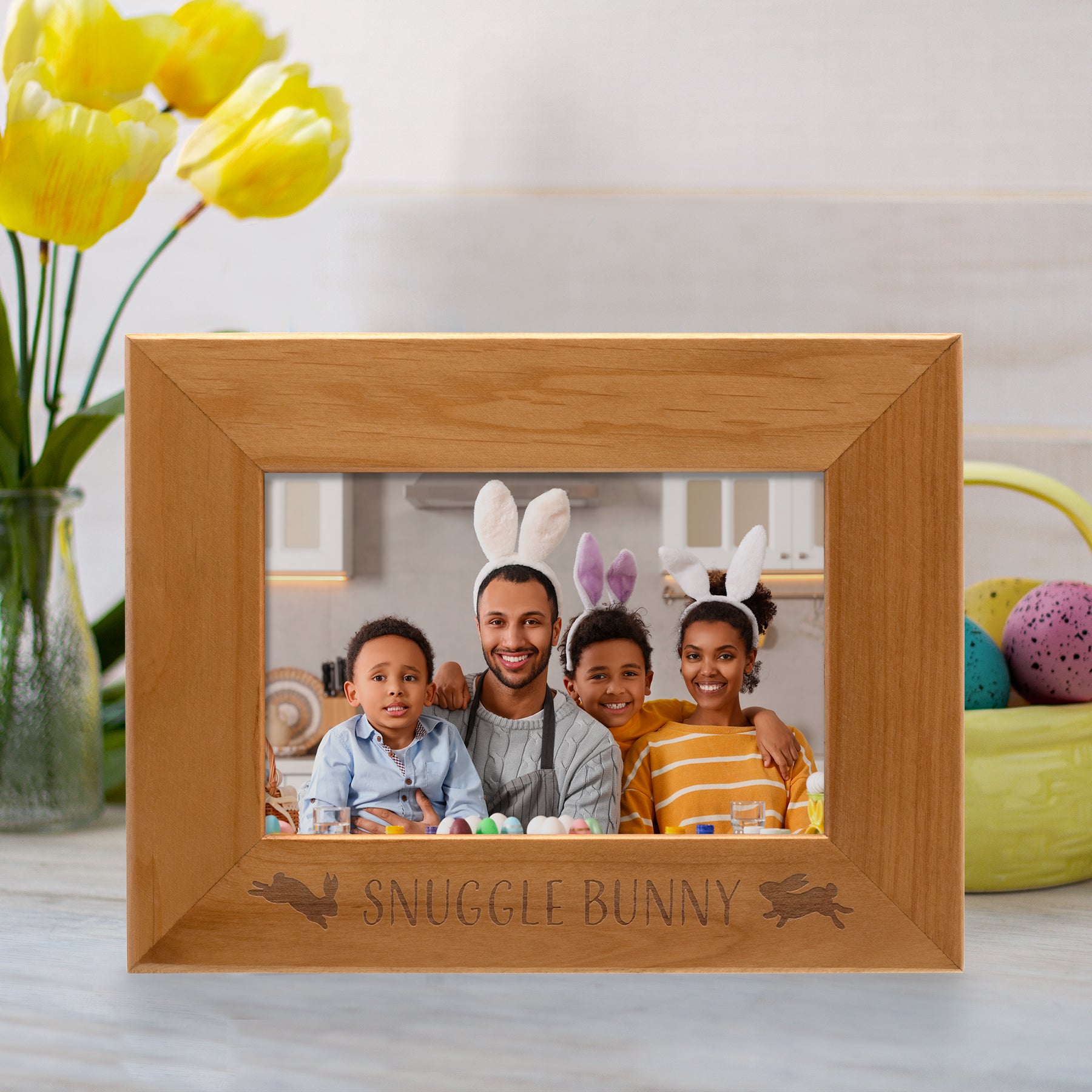 Wooden photo frame with 'Snuggle Bunny' engraving, family photo inside, yellow tulips on the side.