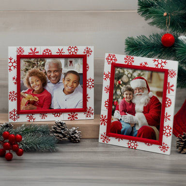 A red and white wooden picture frame with a shiplap design and red snowflake decorations shown in vertical and horizontal orientations on a festive back drop.