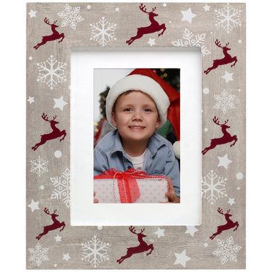A rustic wooden picture frame with a reindeer and Christmas-themed pattern, displaying a photo of a person wearing a Santa hat.